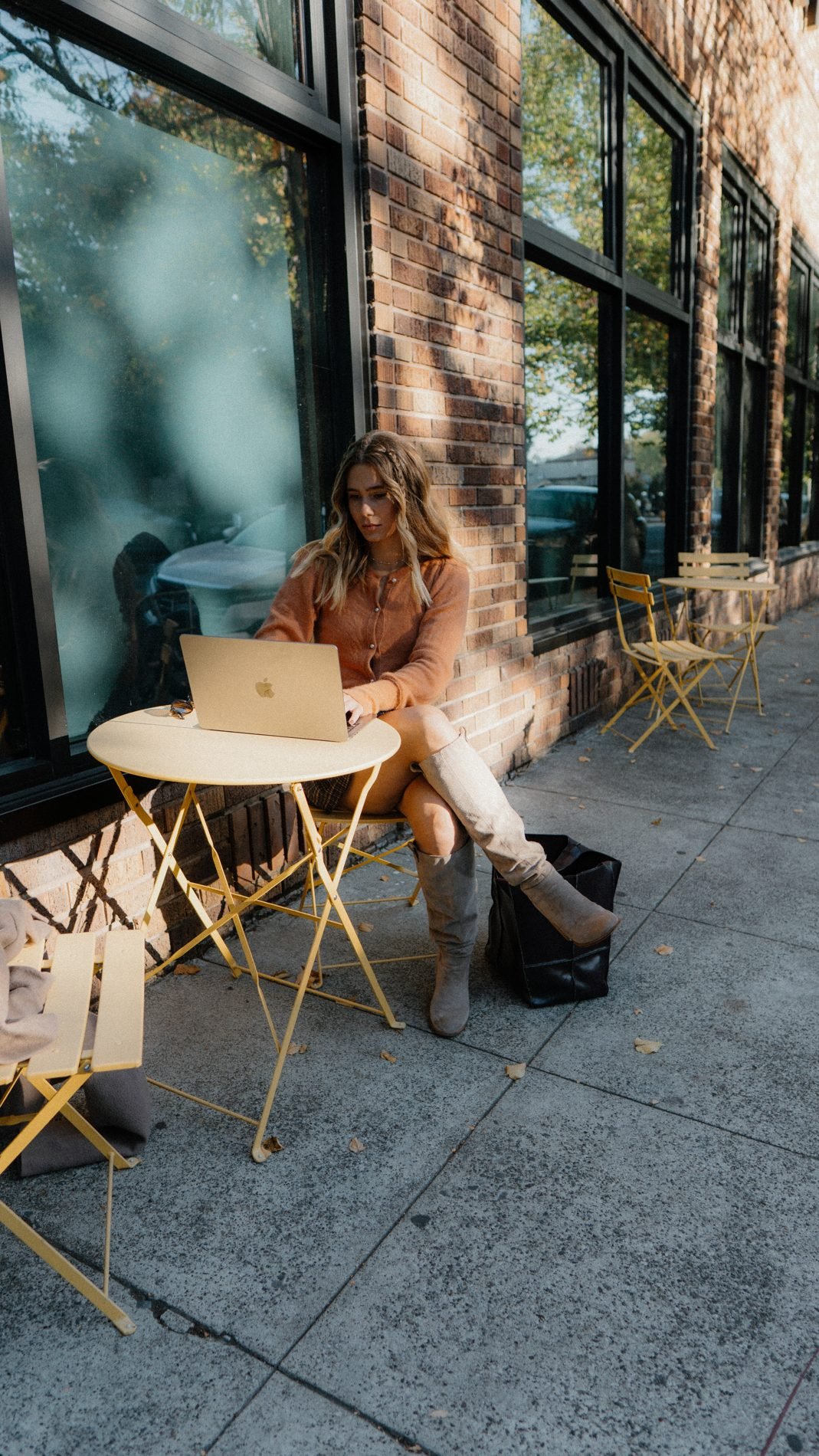 Ashley Robutz working on her laptop at a sidewalk cafe table